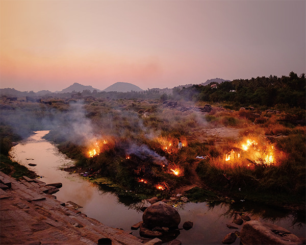 Locals burning grass along the river in Hampi. Karnataka, India