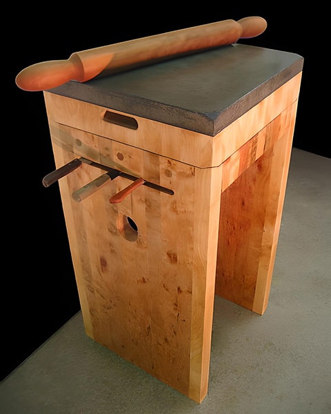 A reversible slab of end-grain maple and concrete provides both cutting and pastry rolling surfaces. Its base extends the vertical grain, and elegantly stores knives and a cherry rolling pin.